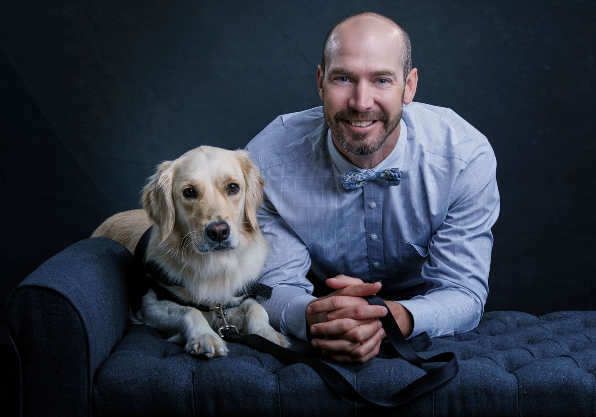 Man holding a golden retriever therapy dog at Thrive Family Dental in Wilmington, NC